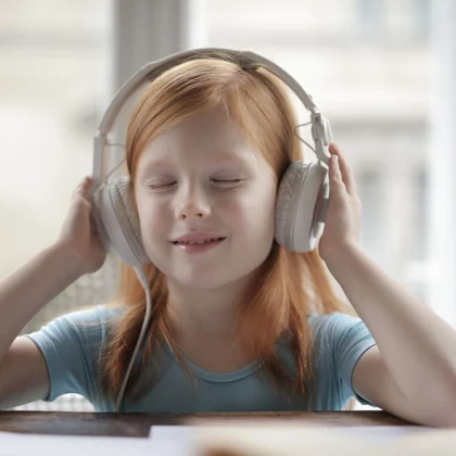 Anak perempuan memakai headphone, foto stok bukan peserta kelas Edu Ceria