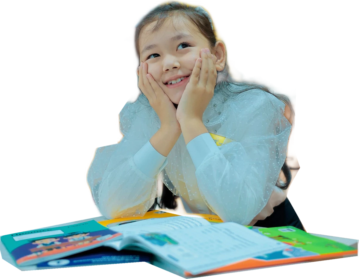 Anak perempuan tersenyum di meja dengan buku terbuka, foto stok ilustratif